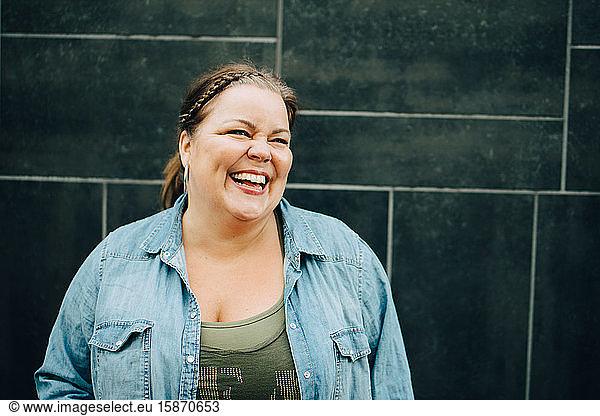 Smiling mature woman standing against wall