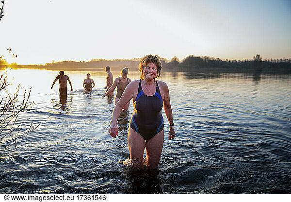 Smiling mature woman standing in water with male and female friends in background