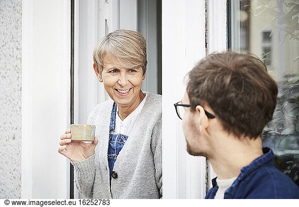 Smiling mature woman with male colleague at entrance of art studio
