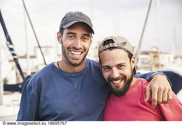 Smiling men wearing caps at harbor
