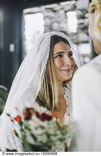 Smiling mid adult bride in wedding dress looking at groom