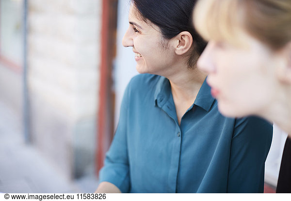 Smiling mid adult businesswoman with female colleague looking away outside office