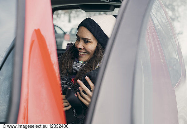 Smiling mid adult woman sitting in car seen through open door