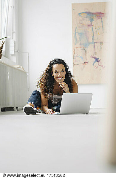 Smiling mid adult woman using laptop on floor at home