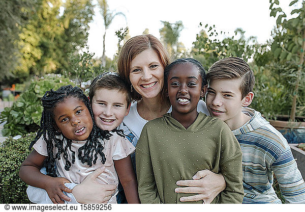 Smiling mid-40's mom & and four happy children- mixed race family