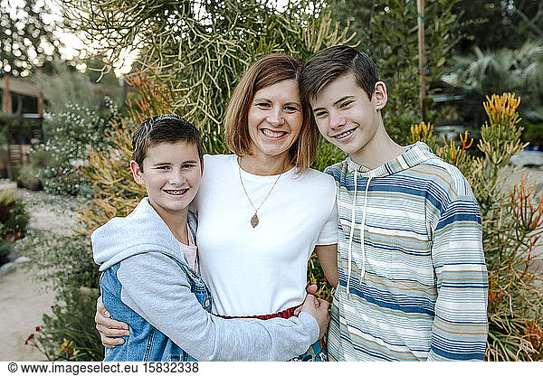 Smiling mom hugging happy clean-cut sons with braces blue shirts
