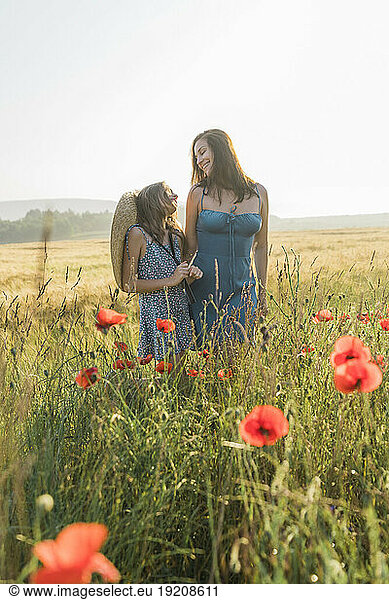 Smiling mother and daughter spending leisure time in poppy field