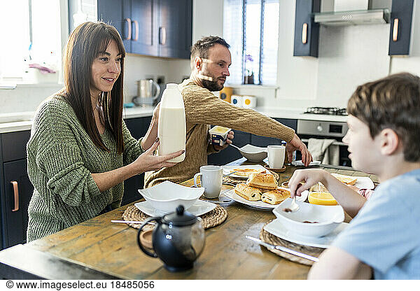 Smiling mother and father having breakfast with son at home