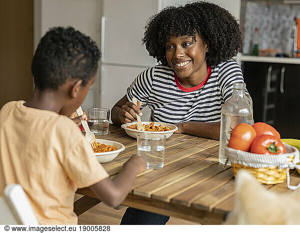 Smiling mother and son having meal together at home