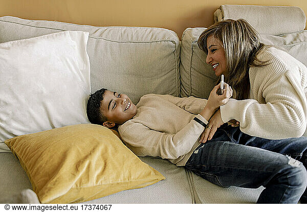 Smiling mother and son playing over sofa at home