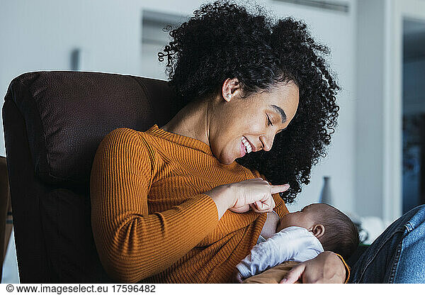 Smiling mother breastfeeding son in living room
