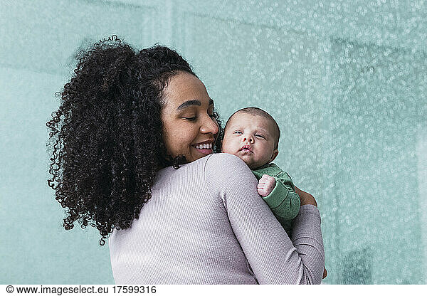 Smiling mother carrying son by wall