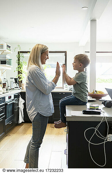 Smiling mother playing with son in kitchen