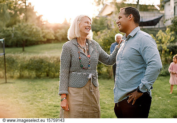 Smiling mother talking with son while standing in backyard