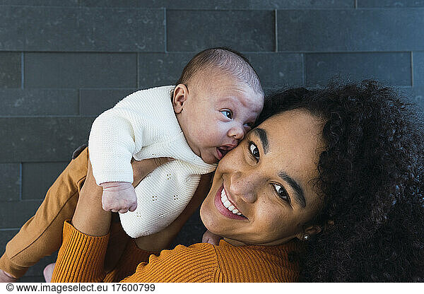 Smiling mother with baby boy by wall