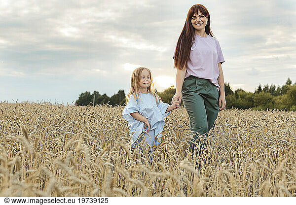 Smiling mother with daughter walking amidst field