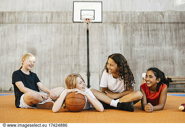 Smiling multi-ethnic female friends spending leisure time at basketball court