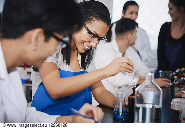 Smiling multi-ethnic students mixing solutions at chemistry laboratory