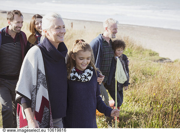 Smiling multi-generation family walking in beach grass