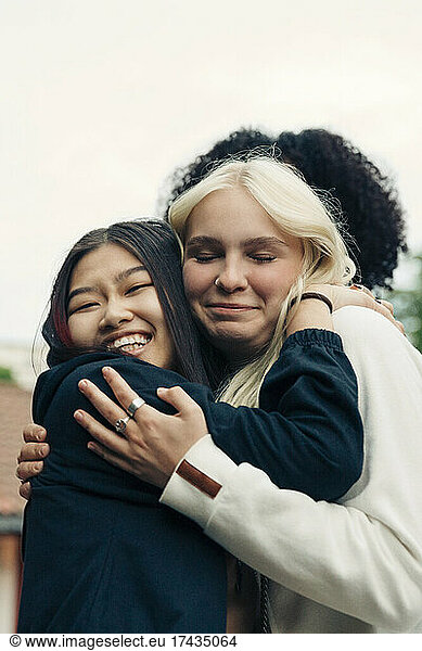 Smiling multiracial female friends embracing in park
