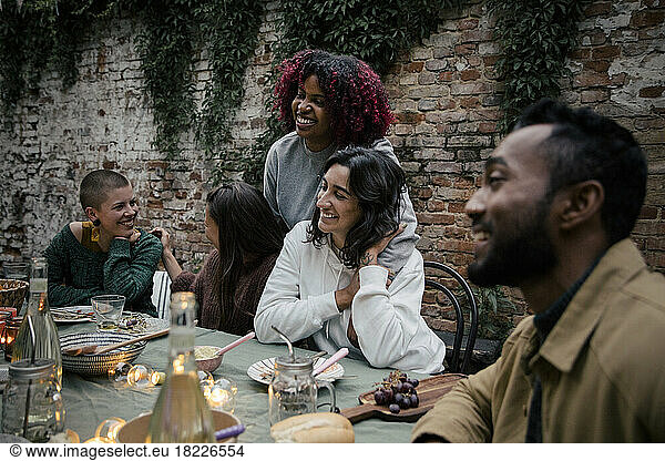 Smiling multiracial male and female friends talking with each other during dinner party