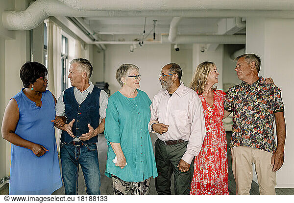 Smiling multiracial senior couples talking while looking at each other in dance class