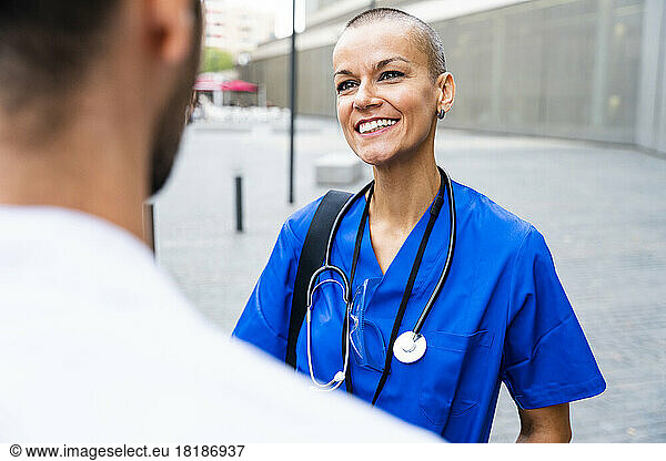 Smiling nurse with stethoscope talking to colleague