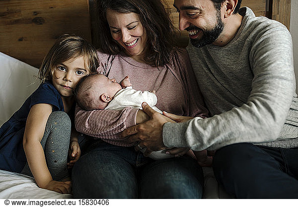 Smiling parents and 4 yr old admiring newborn baby