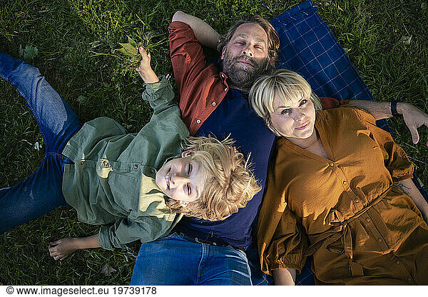 Smiling parents relaxing with son in park