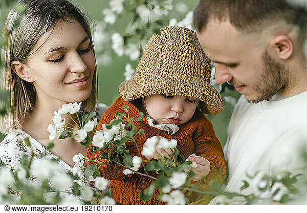 Smiling parents with child spending leisure time in garden