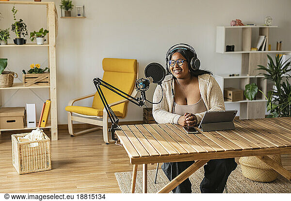 Smiling podcaster sitting at desk at home office
