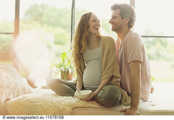 Smiling pregnant couple eating and talking