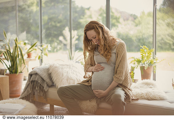 Smiling pregnant woman holding stomach