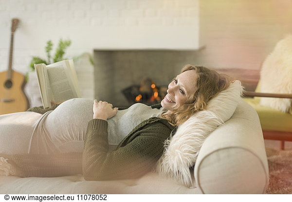 Smiling pregnant woman laying relaxing reading book