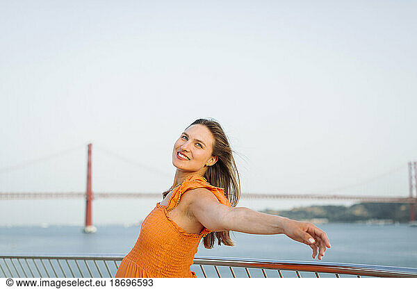 Smiling pregnant woman with arm outstretched near railing