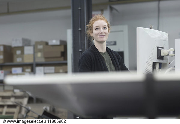 Smiling print worker working by printing equipment at press