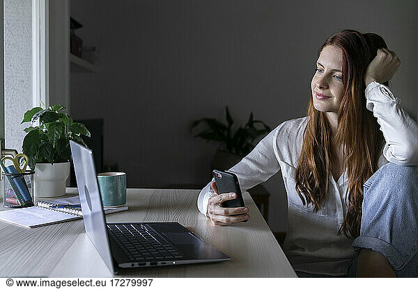 Smiling psychologist using mobile phone while sitting at home