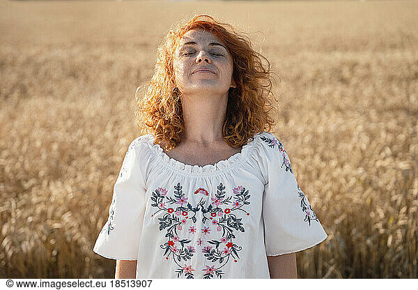 Smiling redhead woman standing in field