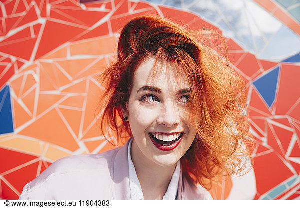 Smiling redhead young woman against mosaic wall