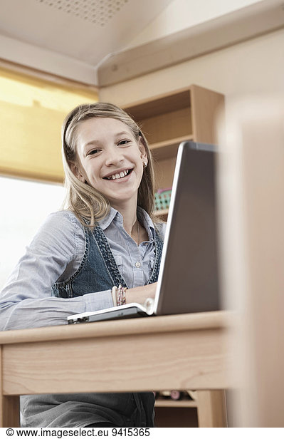 Smiling schoolgirl with laptop
