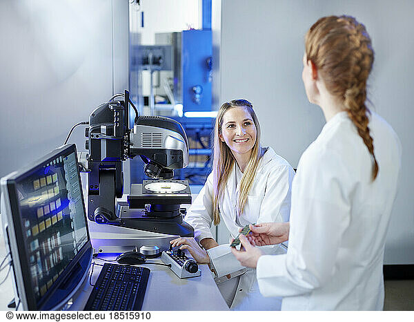 Smiling scientist discussing with technician at E-Laboratory