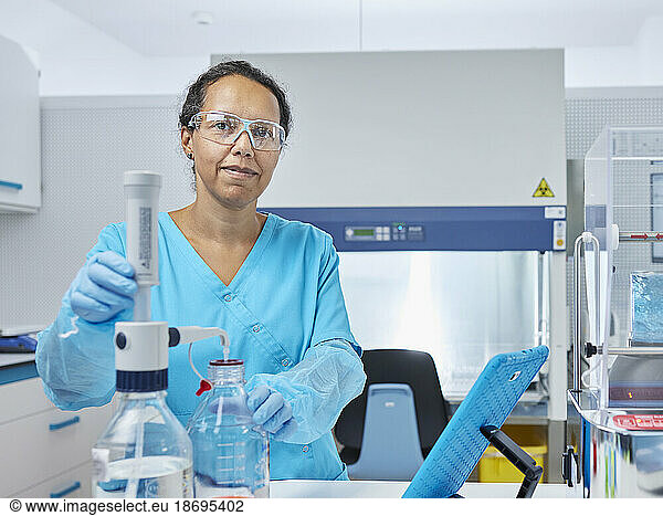 Smiling scientist filling chemical in bottle at microbiological laboratory