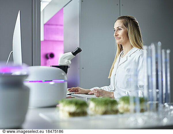 Smiling scientist in front of microscope on desktop at laboratory