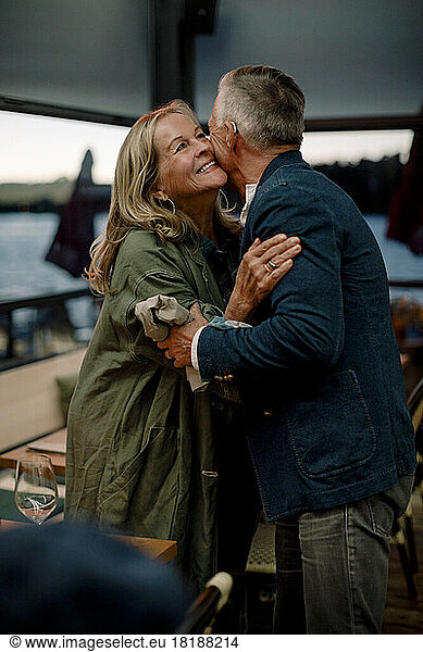 Smiling senior blond woman embracing man in restaurant