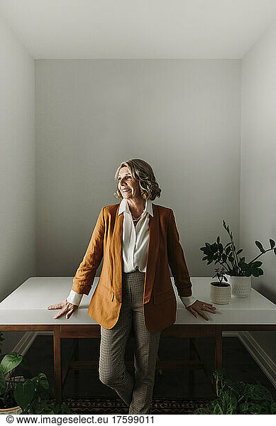 Smiling senior businesswoman standing by desk at home