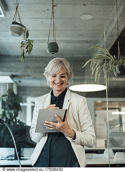Smiling senior businesswoman using tablet PC at office