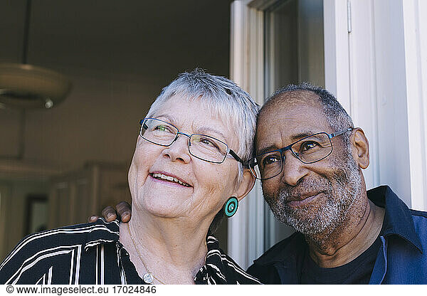 Smiling senior couple looking away against doorway