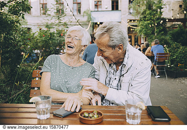 Smiling senior couple tourist sitting at restaurant in city