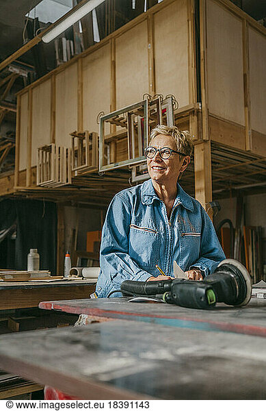 Smiling senior female carpenter contemplating at workshop