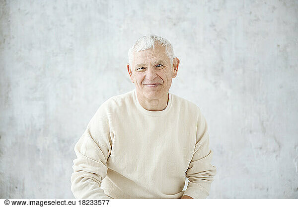 Smiling senior man in front of wall at home